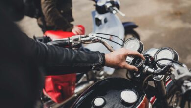Motorcycle with rider adjusting the speedometer in an outdoor setting, adventure biking, outdoor exploration, motorbike gear.
