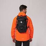 Lightweight black hiking backpack with outdoor gear on model in orange jacket.