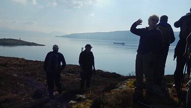 Serene outdoor landscape with hikers overlooking a calm lake and distant islands, perfect for outdoor adventure and nature exploration.