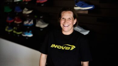 Bright smiling woman in outdoor footwear store, showcasing sports shoes and outdoor gear.