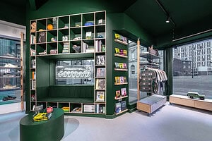 Bright green retail store interior with outdoor clothing, accessories, and books in a modern outdoor shop.