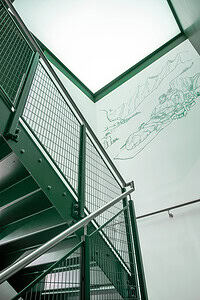 1. Modern green metal staircase with safety railings in an outdoor adventure centre.