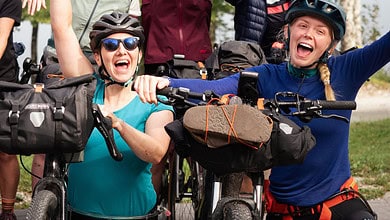 Exciting group of women mountain biking outdoors with helmets and gear in a forest setting.