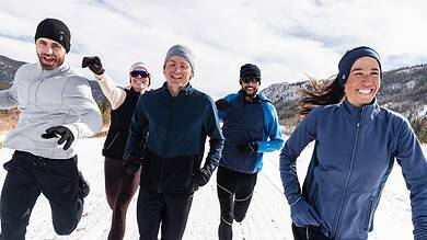 Brightly dressed group running outdoors in snow-capped mountains, enjoying winter adventure and outdoor activities.