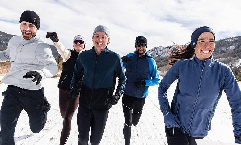 Brightly dressed group running outdoors in snow-capped mountains, enjoying winter adventure and outdoor activities.