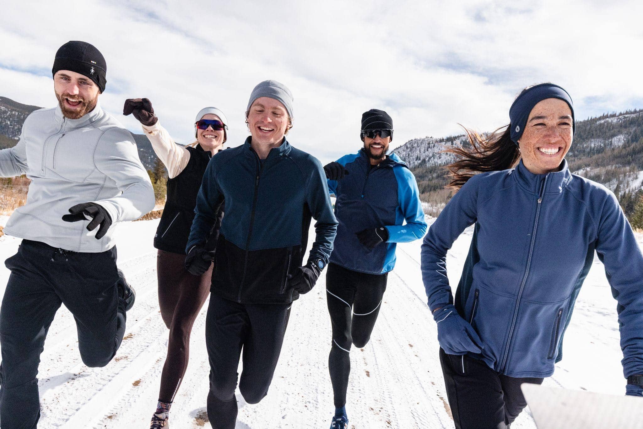 Brightly dressed group running outdoors in snow-capped mountains, enjoying winter adventure and outdoor activities.