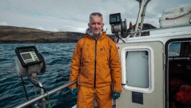 1. Man in orange offshore waterproof jacket on boat during sea expedition.