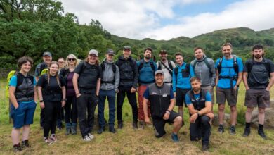 Hiking group outdoors in green landscape, hiking gear, backpacks, scenic mountain view, outdoor adventure, team activity, nature walk.