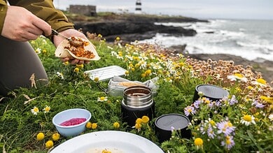 Fresh outdoor picnic setup with sandwiches, flowers, and seaside view at Lighthouse Cove.