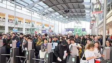 Busy airport security checkpoint with travelers lining up for screening, indoor terminal with high glass ceiling.