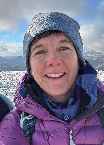 EOCA General Manager in snowy pastures with mountains in the background.