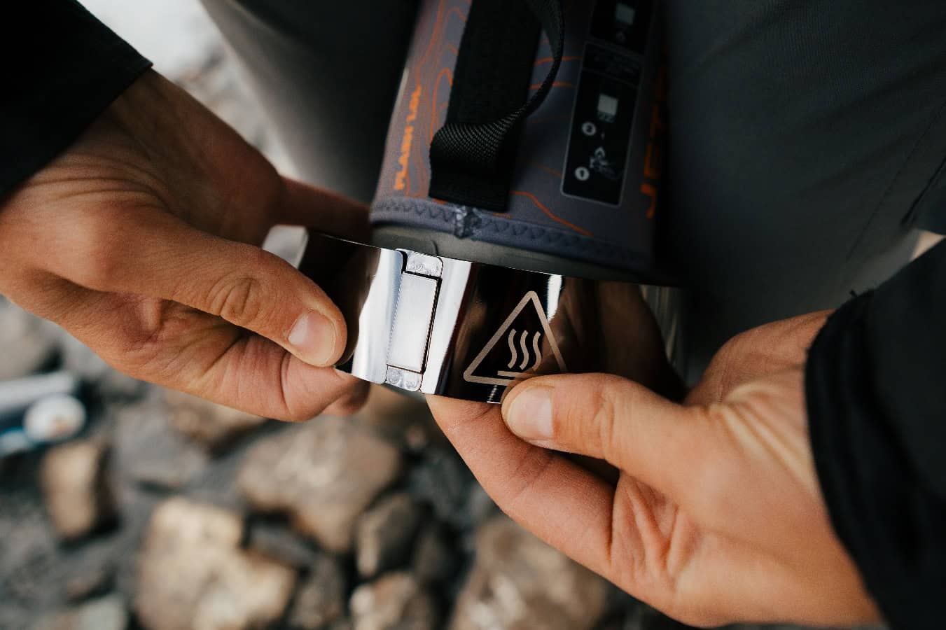Portable camping stove being ignited outdoors for cooking or heating.