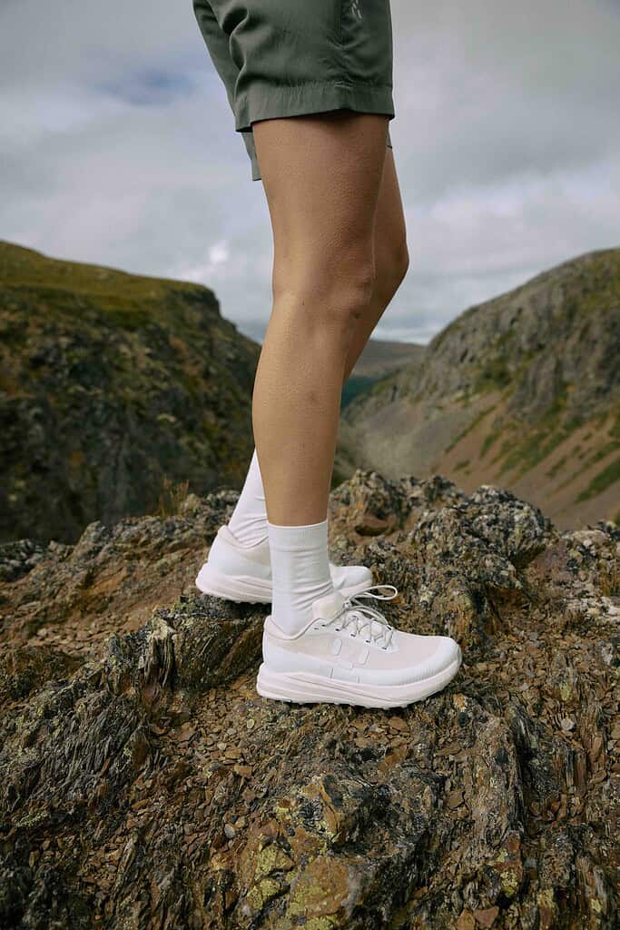 Woman's white lightweight hiking shoes on rocky terrain for outdoor adventures.