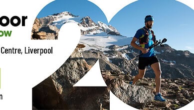 Mountain trail runner navigating rocky terrain with snow-capped peaks in background.