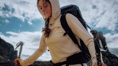 Hiker girl with backpack and trekking poles enjoying outdoor adventure.