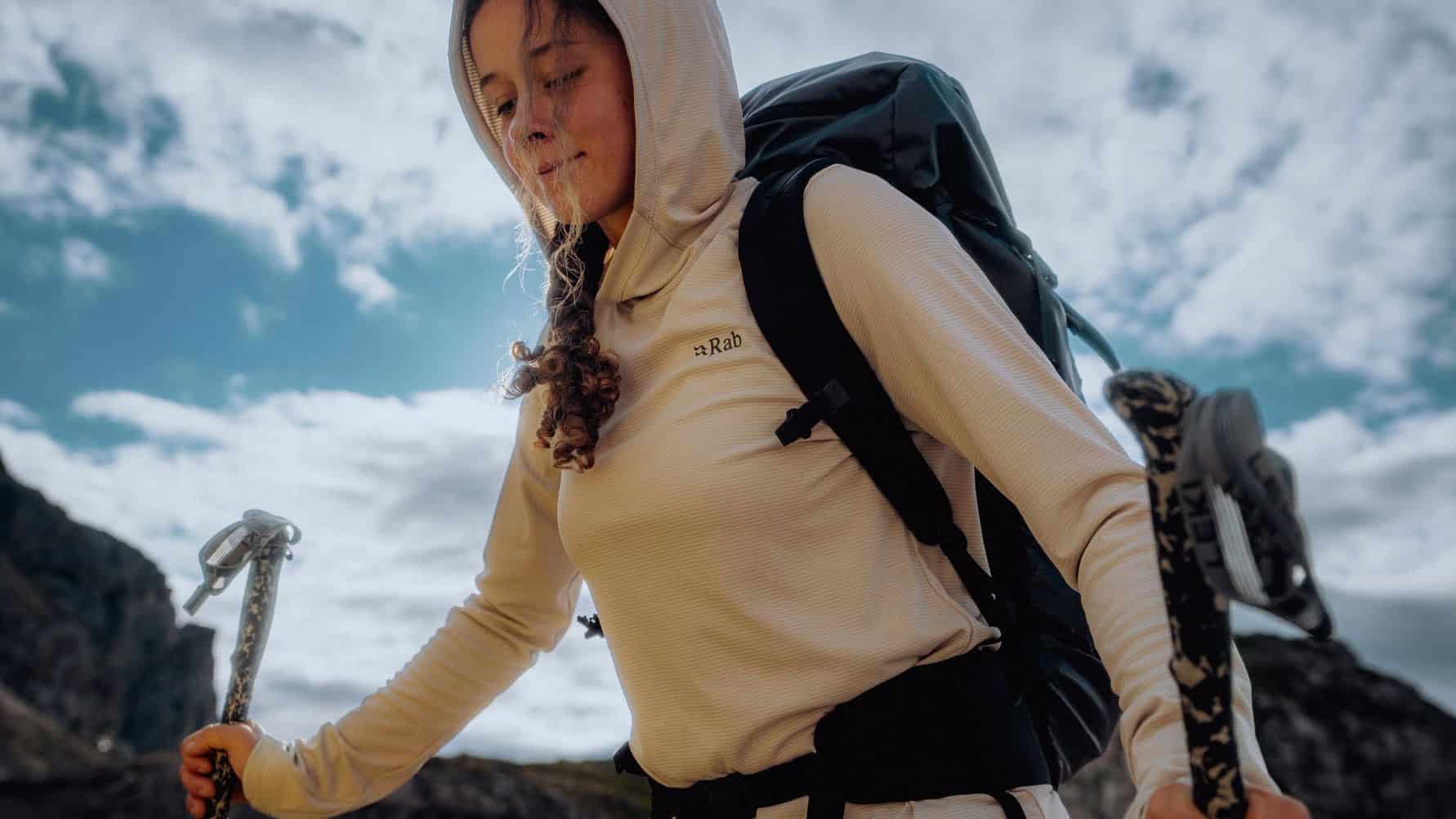 Hiker girl with backpack and trekking poles enjoying outdoor adventure.