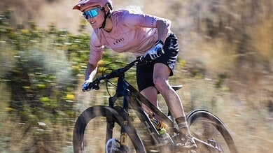 Mountain biking on rugged trails with a cyclist wearing safety gear.