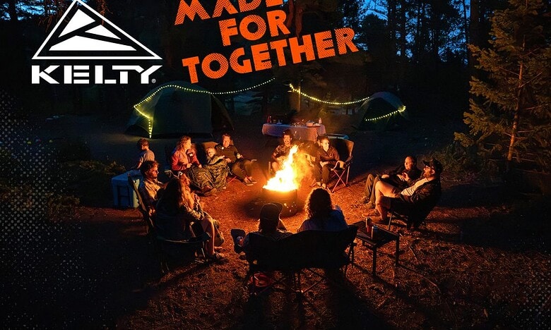 Enjoying a campfire with friends in a forest setting at night, surrounded by tents and outdoor gear.