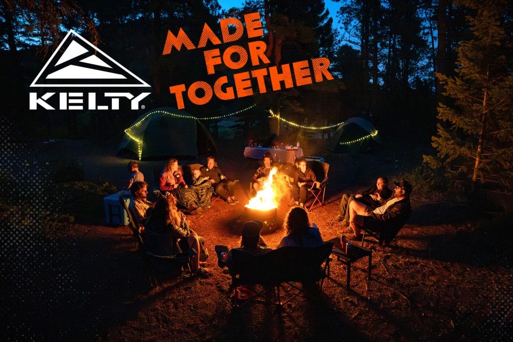 Enjoying a campfire with friends in a forest setting at night, surrounded by tents and outdoor gear.
