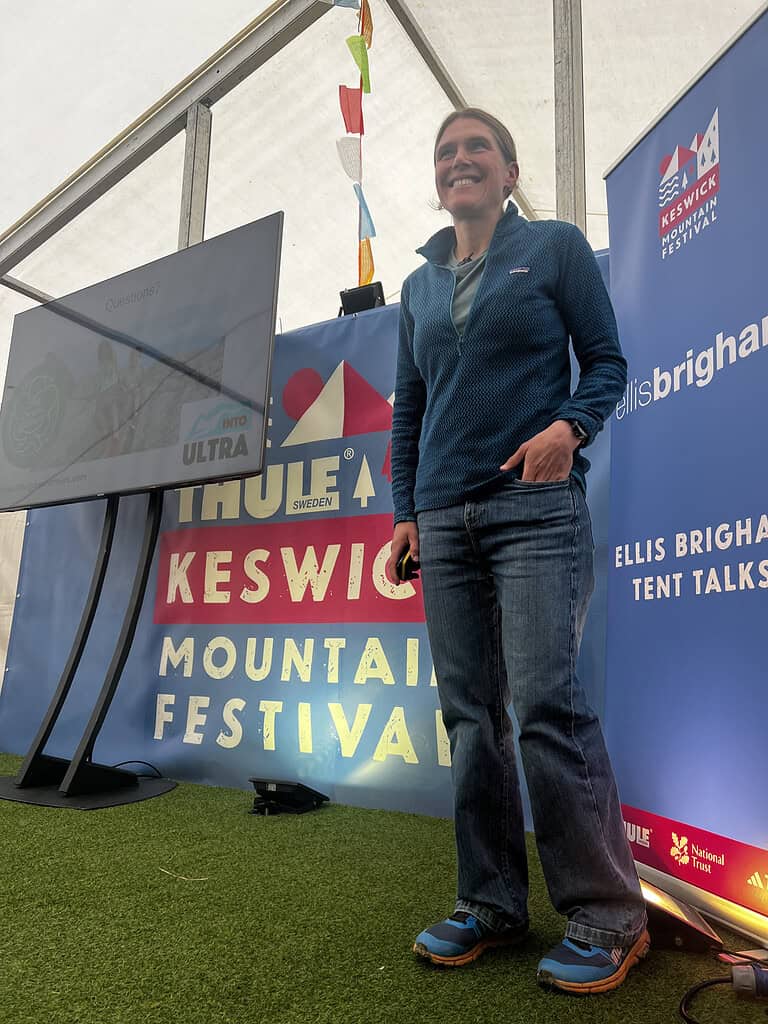 Woman speaking at outdoor mountain festival tent talk event in UK.