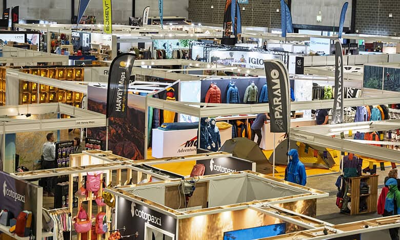 Indoor outdoor gear trade show with various booths and visitors.
