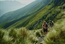 Hikers trekking through lush green mountain landscape in outdoor adventure setting.