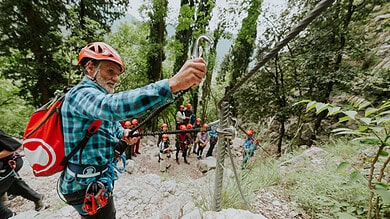 Climber securing safety rope in forest during outdoor adventure activity.
