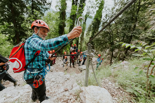 Climber securing safety rope in forest during outdoor adventure activity.