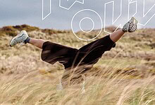 Person doing a handstand in a grassy field during daytime, embracing outdoor adventure.