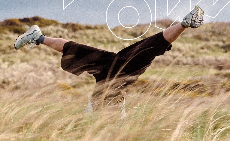 Person doing a handstand in a grassy field during daytime, embracing outdoor adventure.