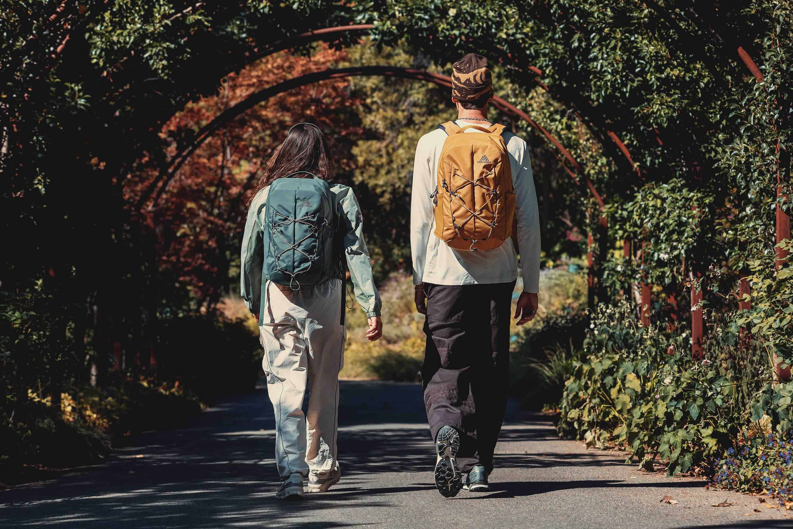 Hikers walking through a lush, green archway on a trail in autumn.