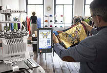 Man using embroidery machine with tablet in a craft shop.