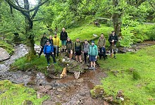 Group of men on a forest walk by a stream during a wellbeing retreat.