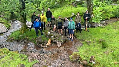 Group of men on a forest walk by a stream during a wellbeing retreat.
