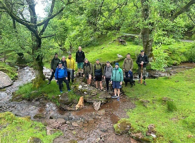 Group of men on a forest walk by a stream during a wellbeing retreat.