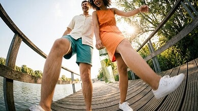 Happy young couple enjoying outdoor walk on a wooden bridge by a lake.